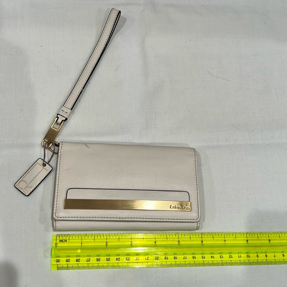 Calvin Klein wristlet in beige with gold accents.